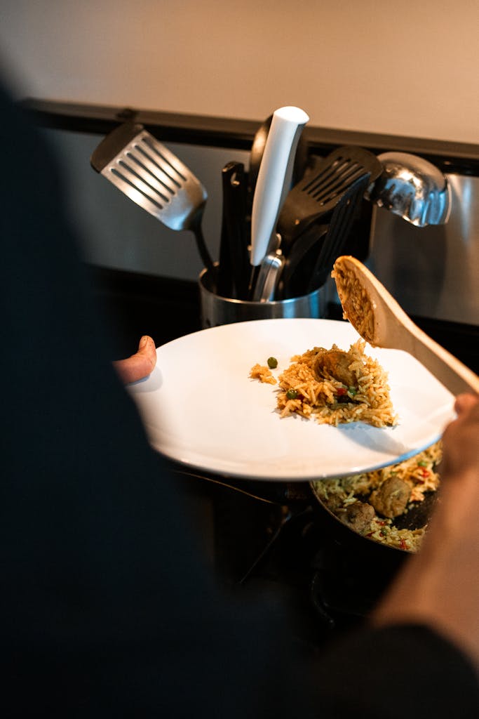 A delicious biryani dish being served onto a white plate. Perfect for food enthusiasts.